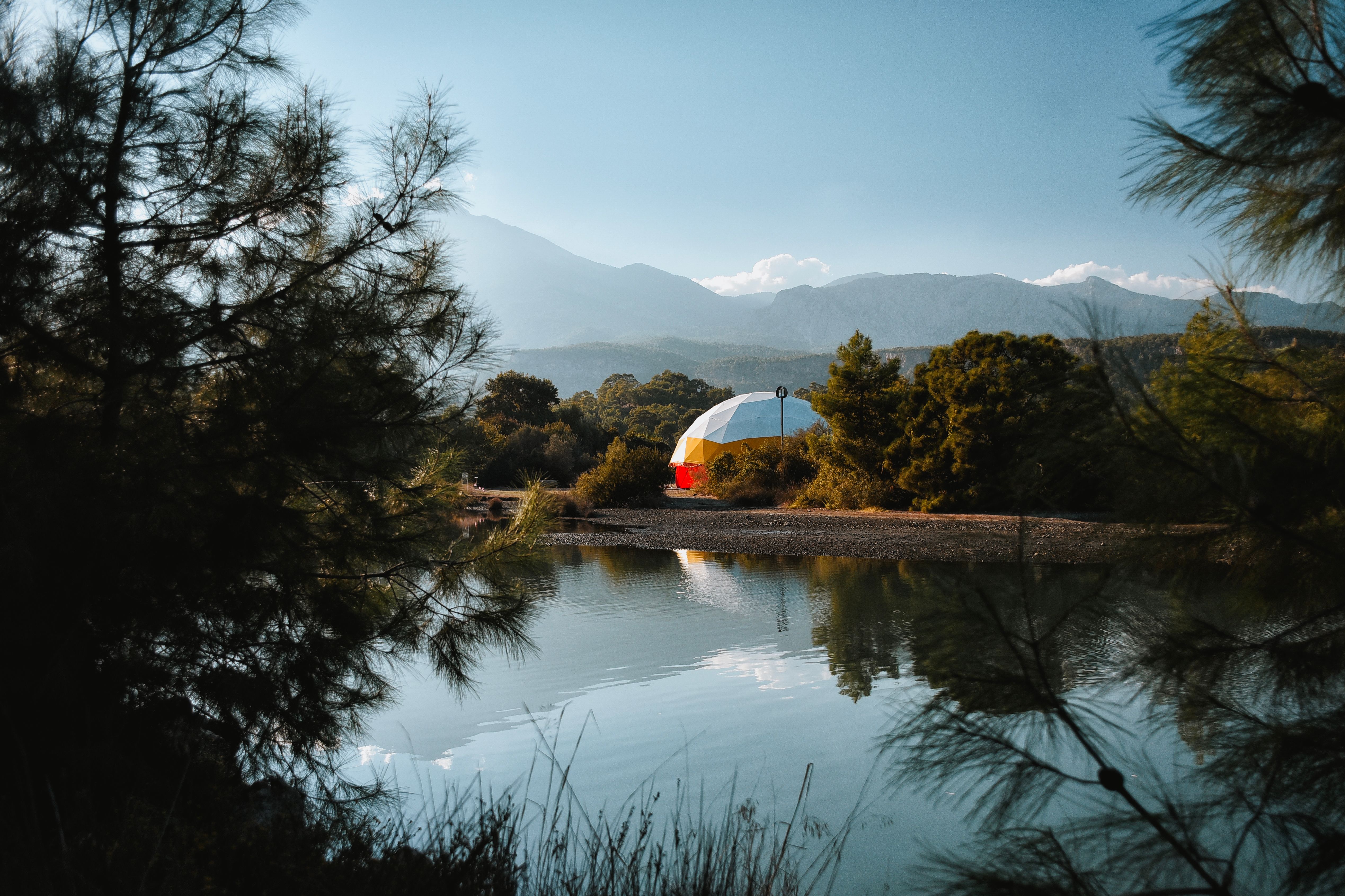 Tenda glamping a cupola sulla riva di un lago con montagne sullo sfondo