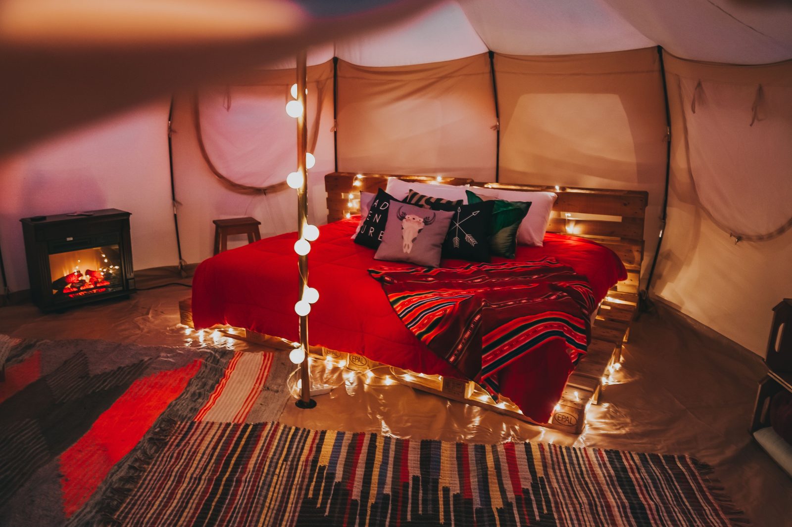 Interno di una tenda glamping con letto matrimoniale, luci soffuse e comfort da hotel