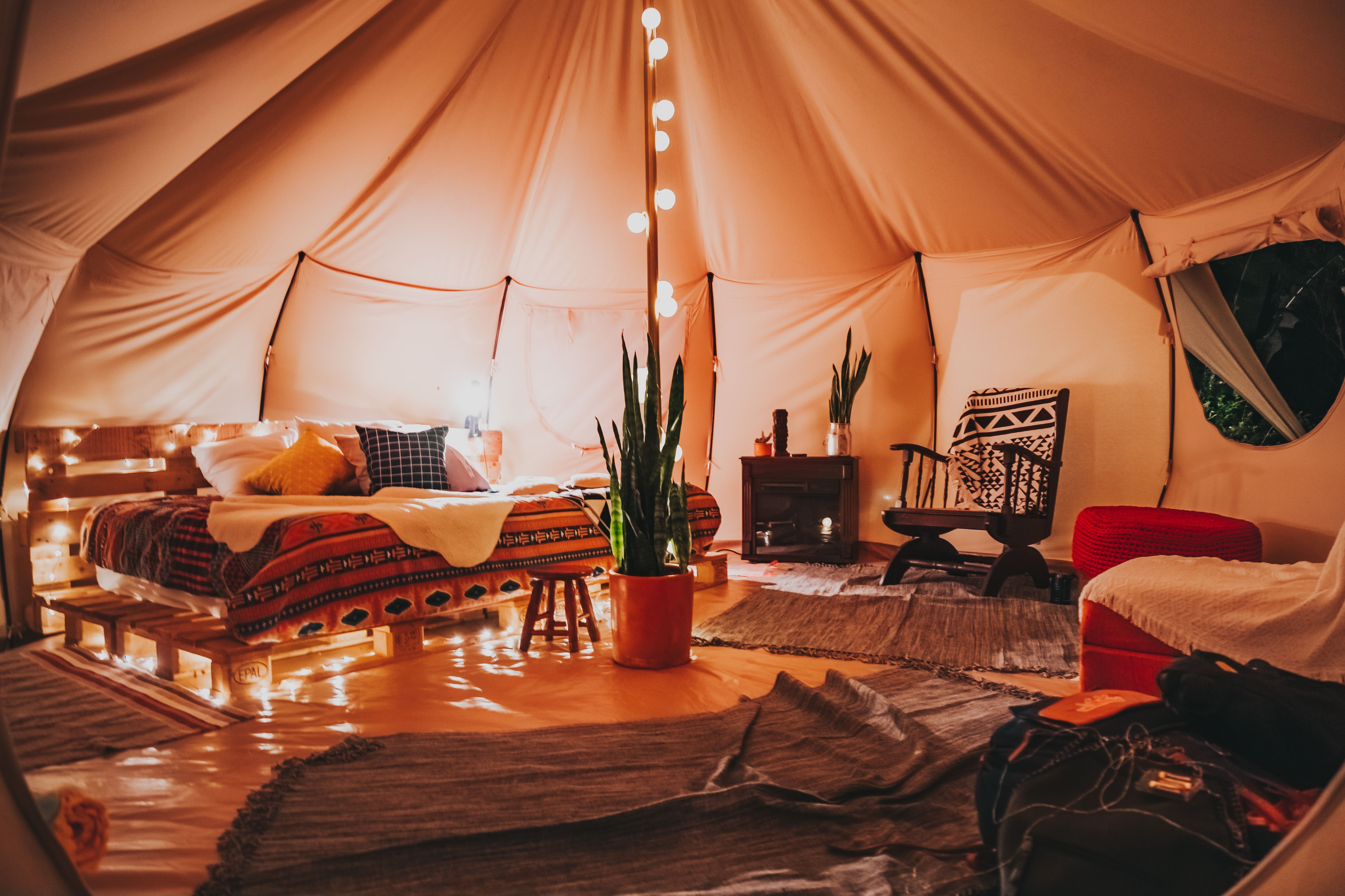 Warmly lit glamping tent interior with string lights in the evening